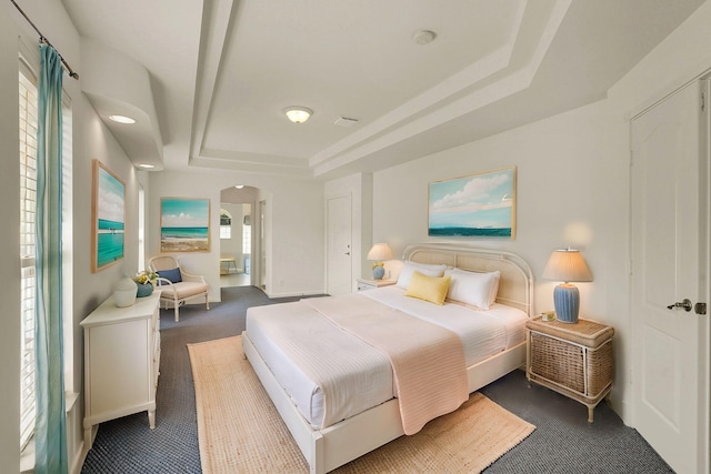 carpeted bedroom with a tray ceiling