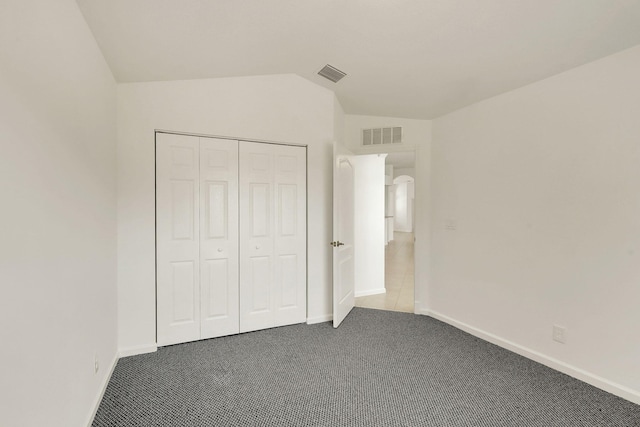 unfurnished bedroom featuring carpet, lofted ceiling, and a closet