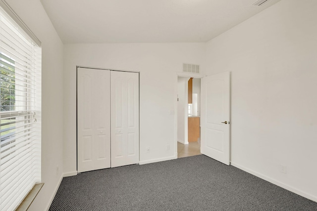 unfurnished bedroom with carpet floors, lofted ceiling, and a closet