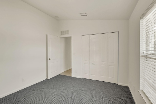 unfurnished bedroom with vaulted ceiling, a closet, and carpet floors