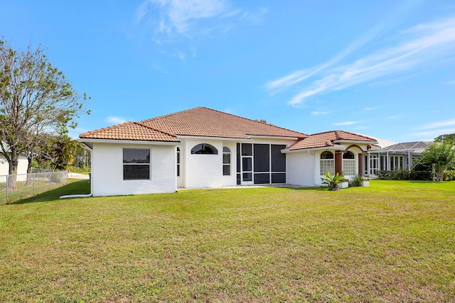 rear view of house with a lawn and a sunroom