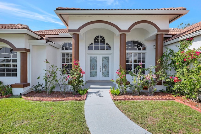 view of exterior entry with french doors and a yard