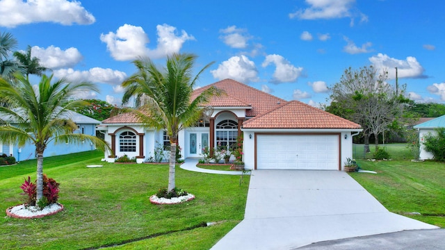 mediterranean / spanish house with a garage and a front lawn