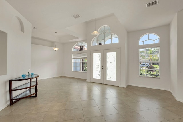 foyer featuring french doors, light tile patterned flooring, and a towering ceiling