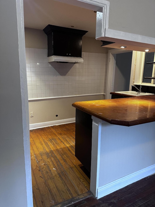 kitchen featuring wooden counters, dark hardwood / wood-style floors, a kitchen breakfast bar, kitchen peninsula, and tasteful backsplash