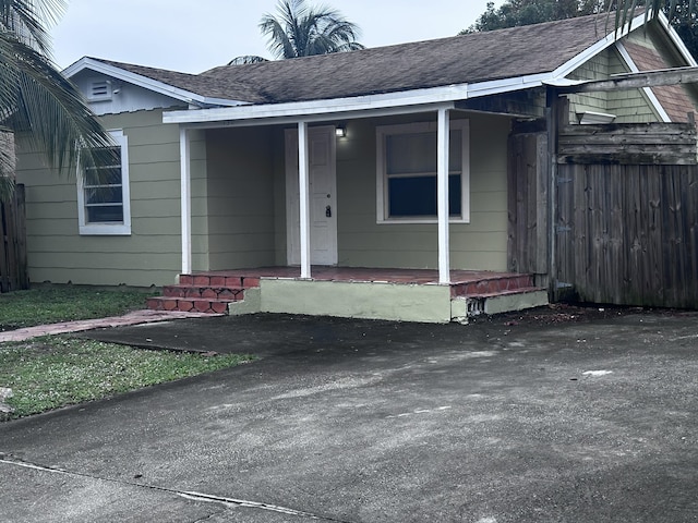 130 NE 4th Ave, Boynton Beach, FL 33435 - view of exterior entry with covered porch and a shingled roof