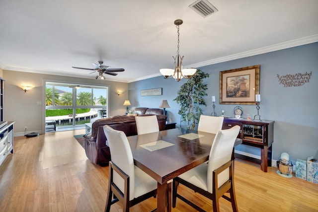 dining area featuring ceiling fan with notable chandelier, light wood-type flooring, and crown molding