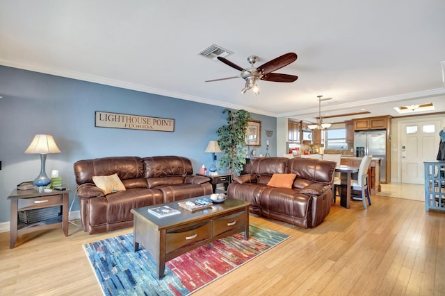 living room with ceiling fan with notable chandelier, light hardwood / wood-style flooring, and crown molding