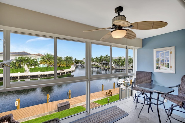 sunroom with a water view, ceiling fan, and a healthy amount of sunlight