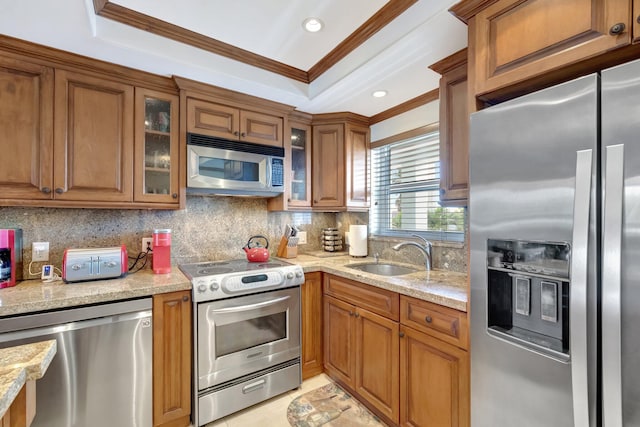 kitchen featuring light stone countertops, tasteful backsplash, ornamental molding, stainless steel appliances, and sink