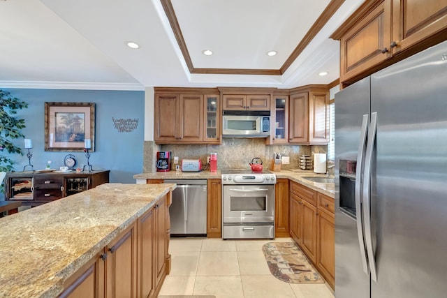 kitchen with light stone counters, crown molding, decorative backsplash, light tile patterned flooring, and appliances with stainless steel finishes