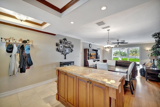 kitchen featuring light stone countertops, light hardwood / wood-style flooring, crown molding, pendant lighting, and ceiling fan with notable chandelier