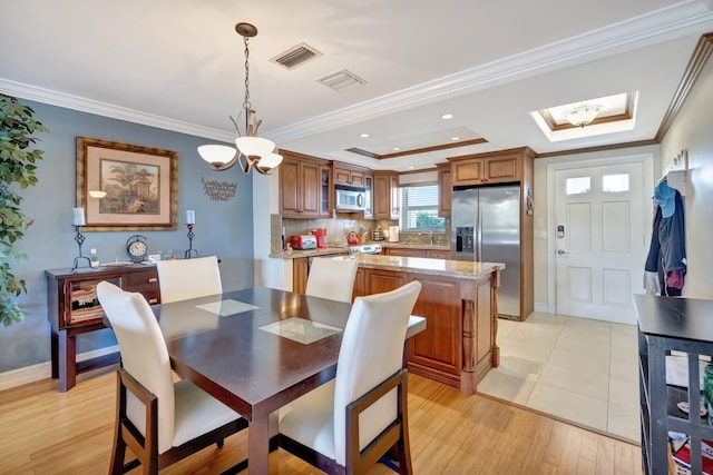 dining area featuring a raised ceiling, light hardwood / wood-style flooring, an inviting chandelier, and ornamental molding