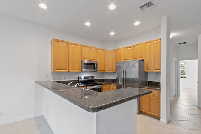 kitchen featuring a peninsula, light tile patterned floors, dark stone countertops, visible vents, and appliances with stainless steel finishes