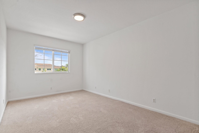 empty room featuring light colored carpet and baseboards