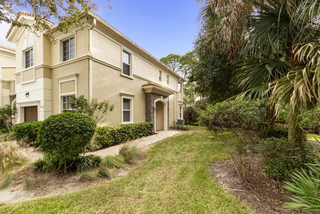 exterior space featuring a garage, a front lawn, and central AC unit