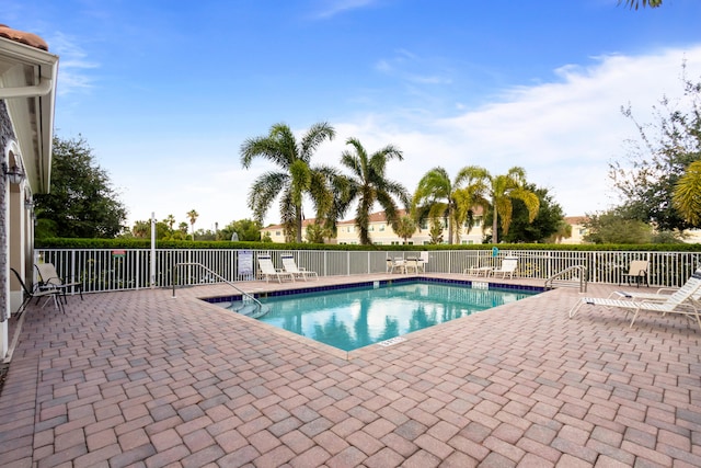 community pool with fence and a patio