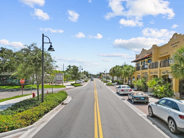 view of road featuring traffic signs, street lighting, curbs, and sidewalks