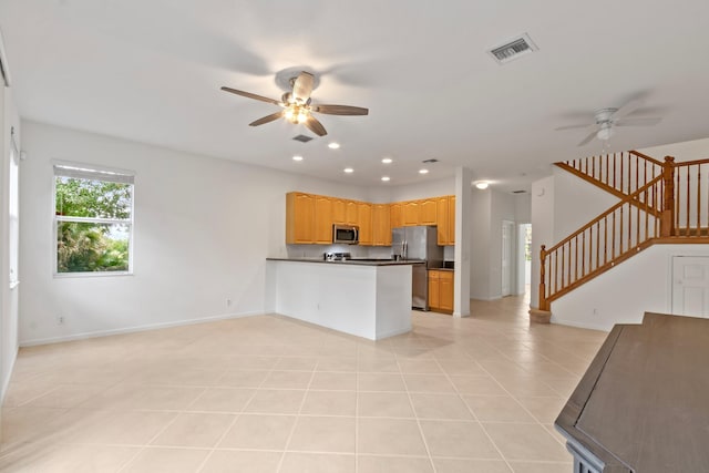 kitchen with a ceiling fan, dark countertops, open floor plan, baseboards, and appliances with stainless steel finishes