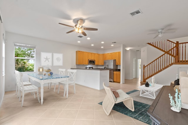 dining room with baseboards, visible vents, ceiling fan, light tile patterned flooring, and stairway
