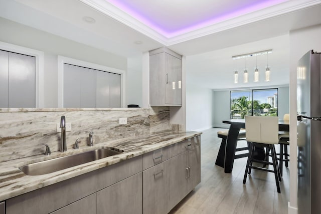 kitchen with stainless steel fridge, light stone countertops, sink, and backsplash