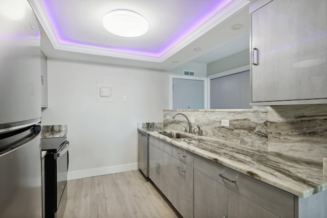 kitchen with sink, tasteful backsplash, light hardwood / wood-style flooring, appliances with stainless steel finishes, and a raised ceiling