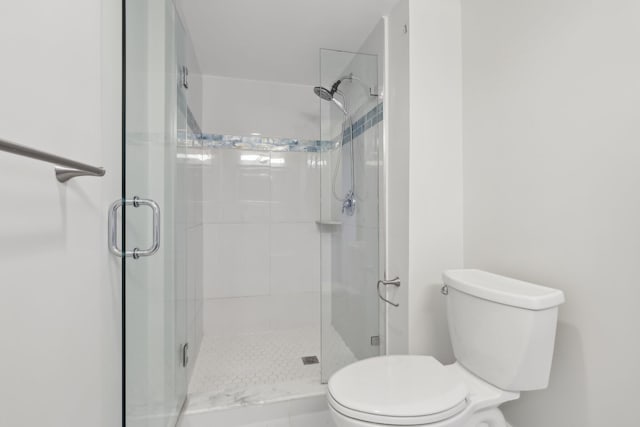 bathroom featuring a shower with door and toilet