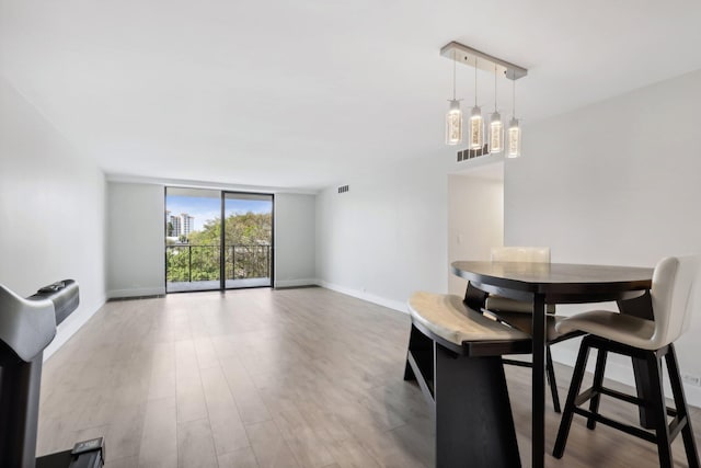 dining area with expansive windows, track lighting, and light wood-type flooring