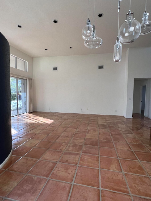 empty room featuring tile patterned floors and a towering ceiling