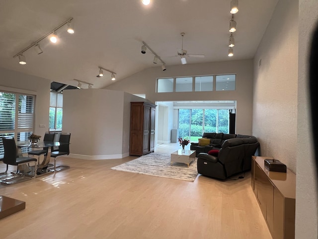 living room featuring rail lighting, ceiling fan, lofted ceiling, and light hardwood / wood-style flooring