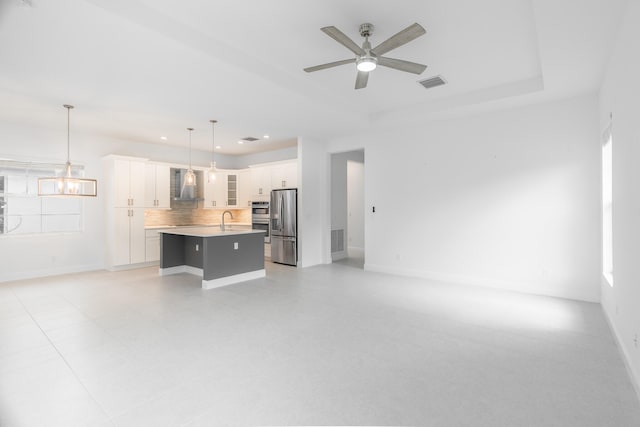 unfurnished living room with light tile patterned flooring, ceiling fan with notable chandelier, and sink