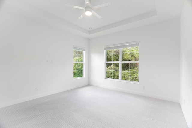 empty room featuring light carpet, ceiling fan, and a raised ceiling