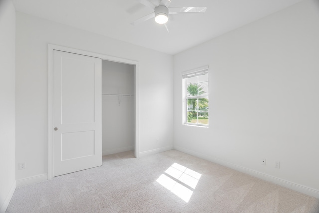 unfurnished bedroom with a closet, light colored carpet, and ceiling fan