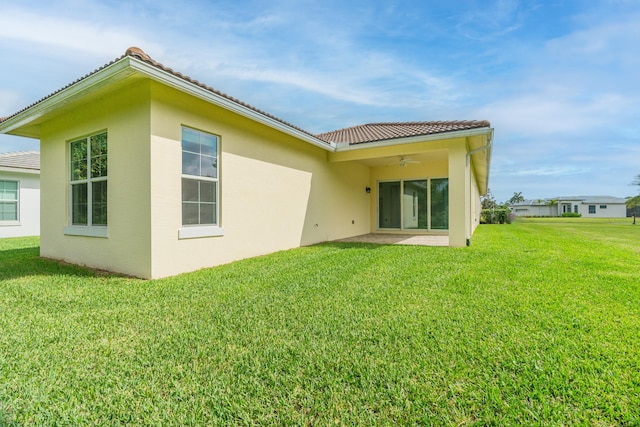 rear view of property featuring a lawn, a patio, and ceiling fan