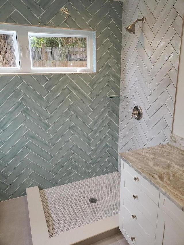 bathroom featuring a tile shower, a healthy amount of sunlight, and vanity