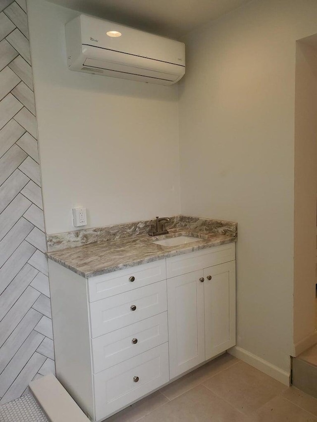 kitchen with white cabinets, light stone counters, light tile patterned floors, an AC wall unit, and sink