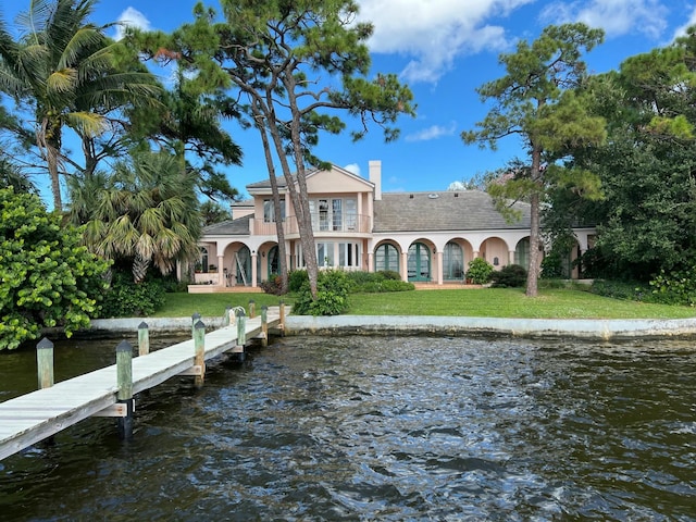 rear view of property featuring a balcony, a lawn, and a water view