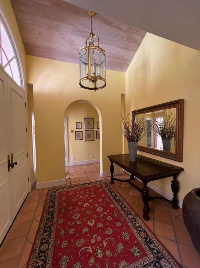 tiled foyer entrance with high vaulted ceiling, wooden ceiling, and a notable chandelier