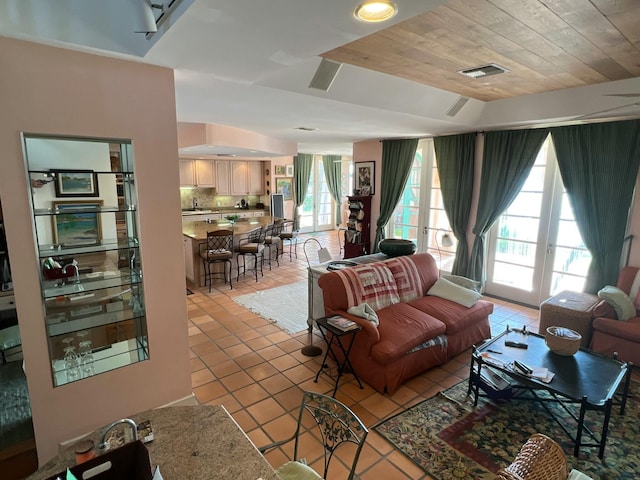 living room with wood ceiling, french doors, and sink