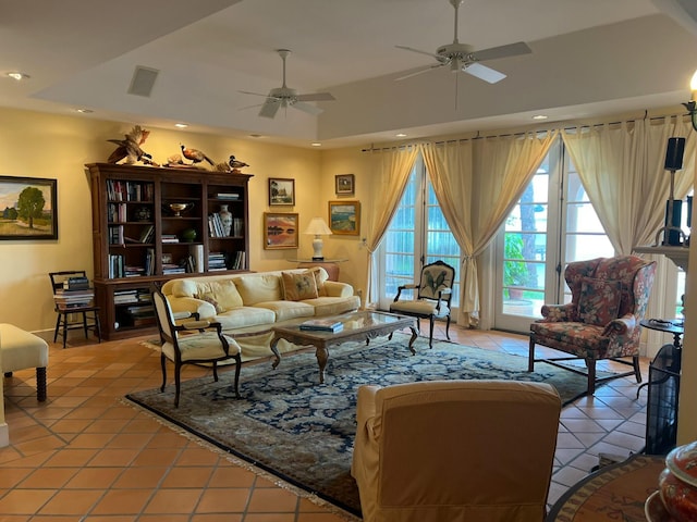 living room with ceiling fan, light tile patterned floors, and a tray ceiling