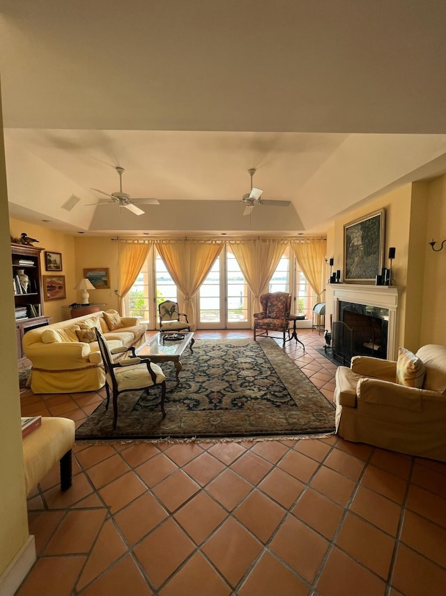 tiled living room featuring a raised ceiling, a high end fireplace, and a wealth of natural light