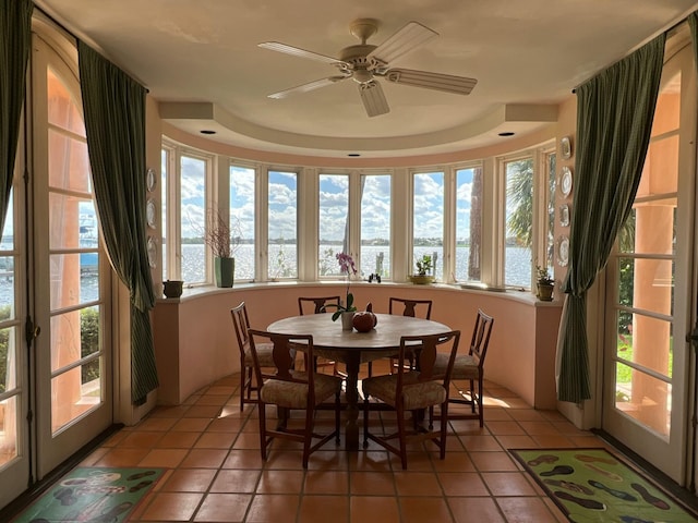 sunroom / solarium with a water view and a tray ceiling