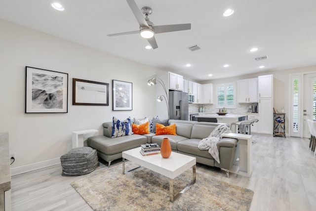 living room featuring ceiling fan, light hardwood / wood-style floors, and plenty of natural light