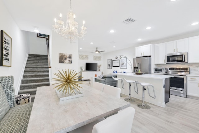 dining area with light hardwood / wood-style flooring and ceiling fan with notable chandelier