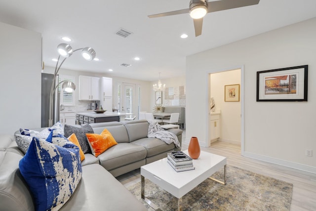 living room featuring light wood-type flooring and ceiling fan with notable chandelier