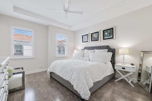 bedroom featuring ceiling fan, a tray ceiling, and dark hardwood / wood-style flooring