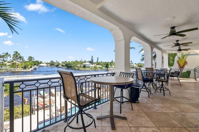 balcony featuring a water view and ceiling fan