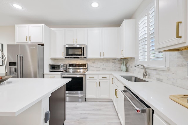 kitchen with white cabinetry, stainless steel appliances, sink, and light wood-type flooring