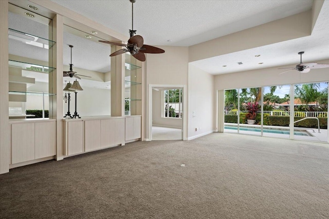 unfurnished living room with baseboards, a textured ceiling, carpet, and ceiling fan