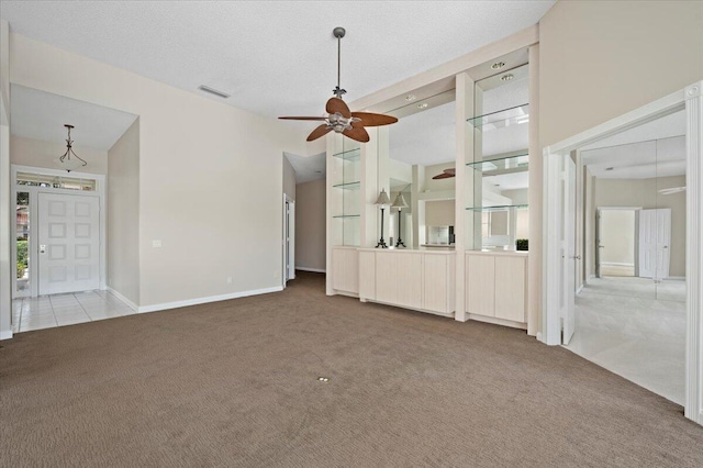 unfurnished living room featuring carpet floors, ceiling fan, visible vents, and baseboards